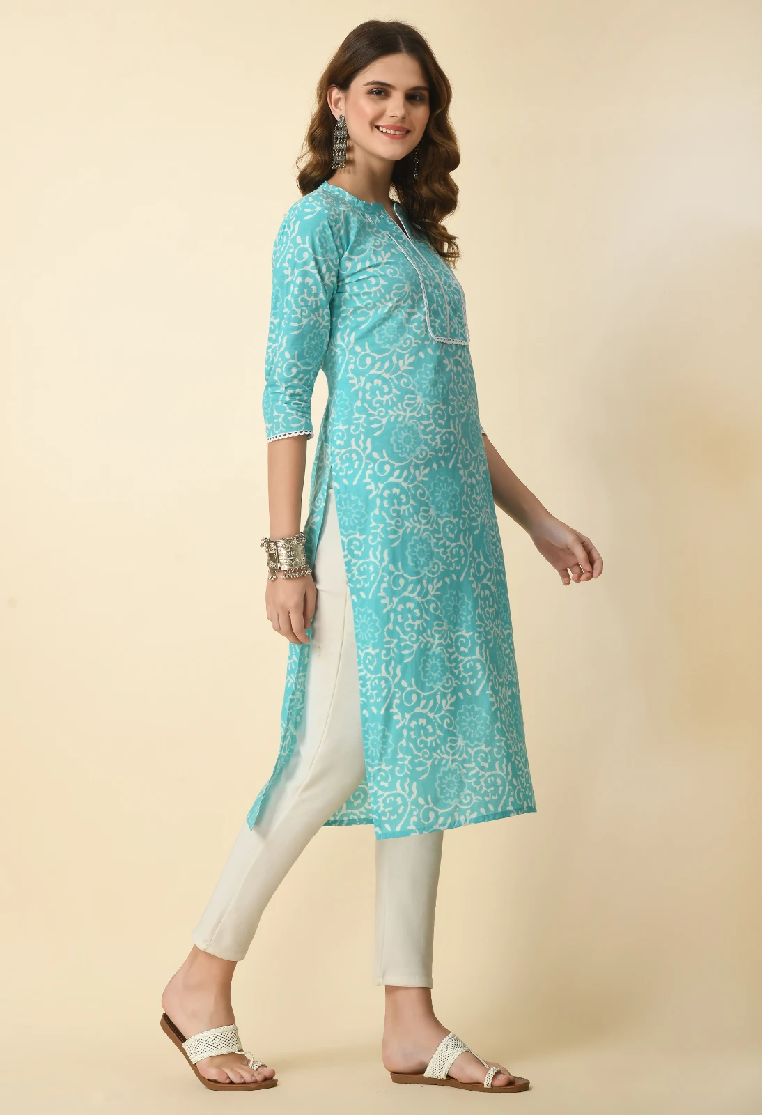 Angled front-side view of turquoise printed kurta with split neckline, bib-style lace detail and white trousers