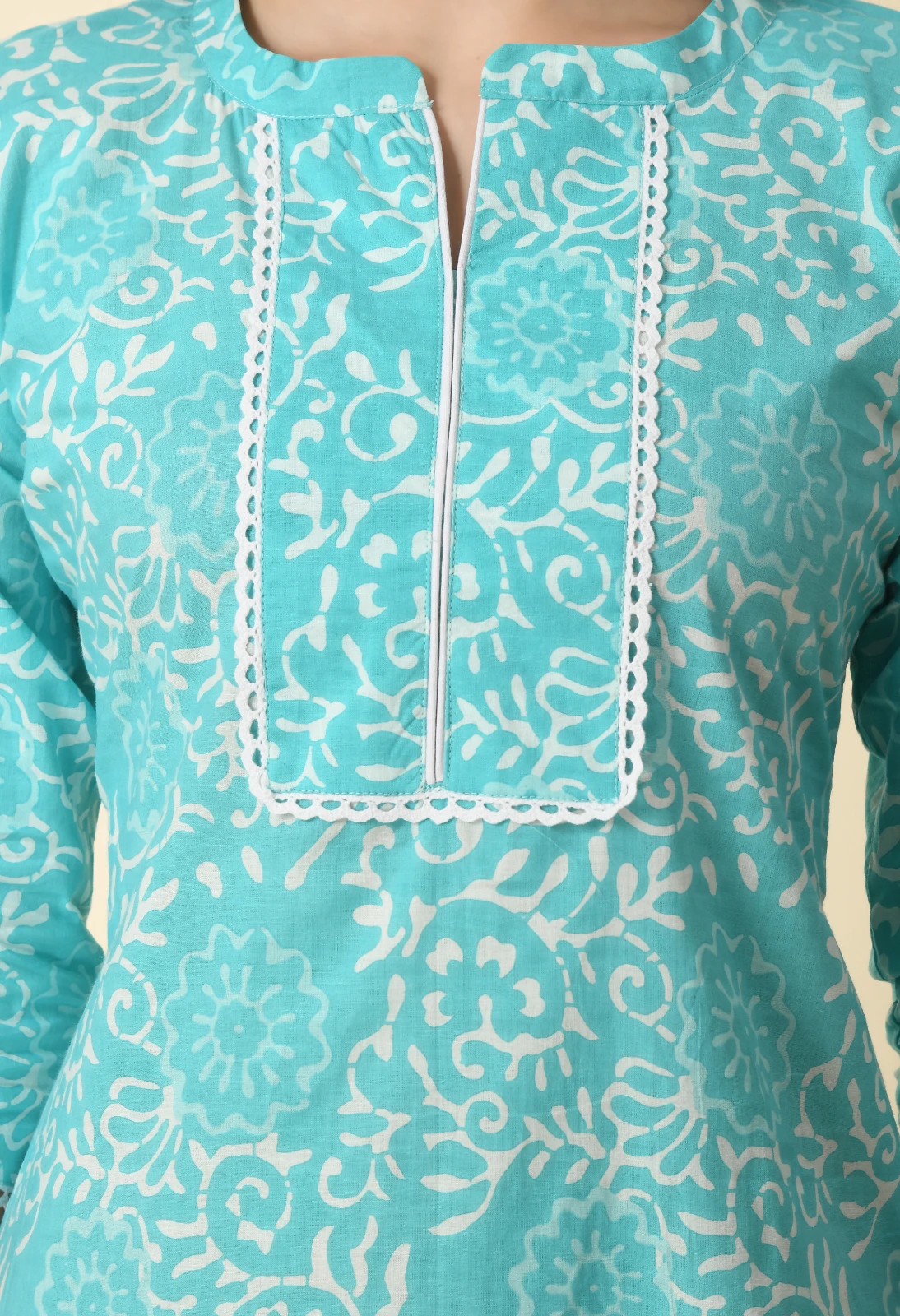 Close-up of the kurta neckline with white lace edging, slit placket and turquoise floral block print