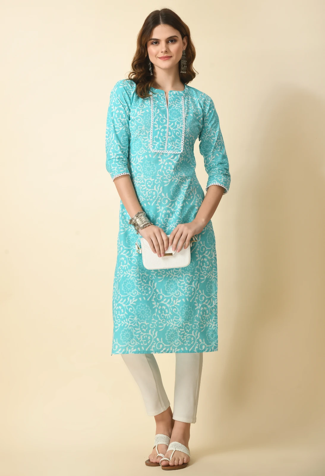 Full-length styled view of the turquoise printed kurta with white pants, flats and a small white handbag
