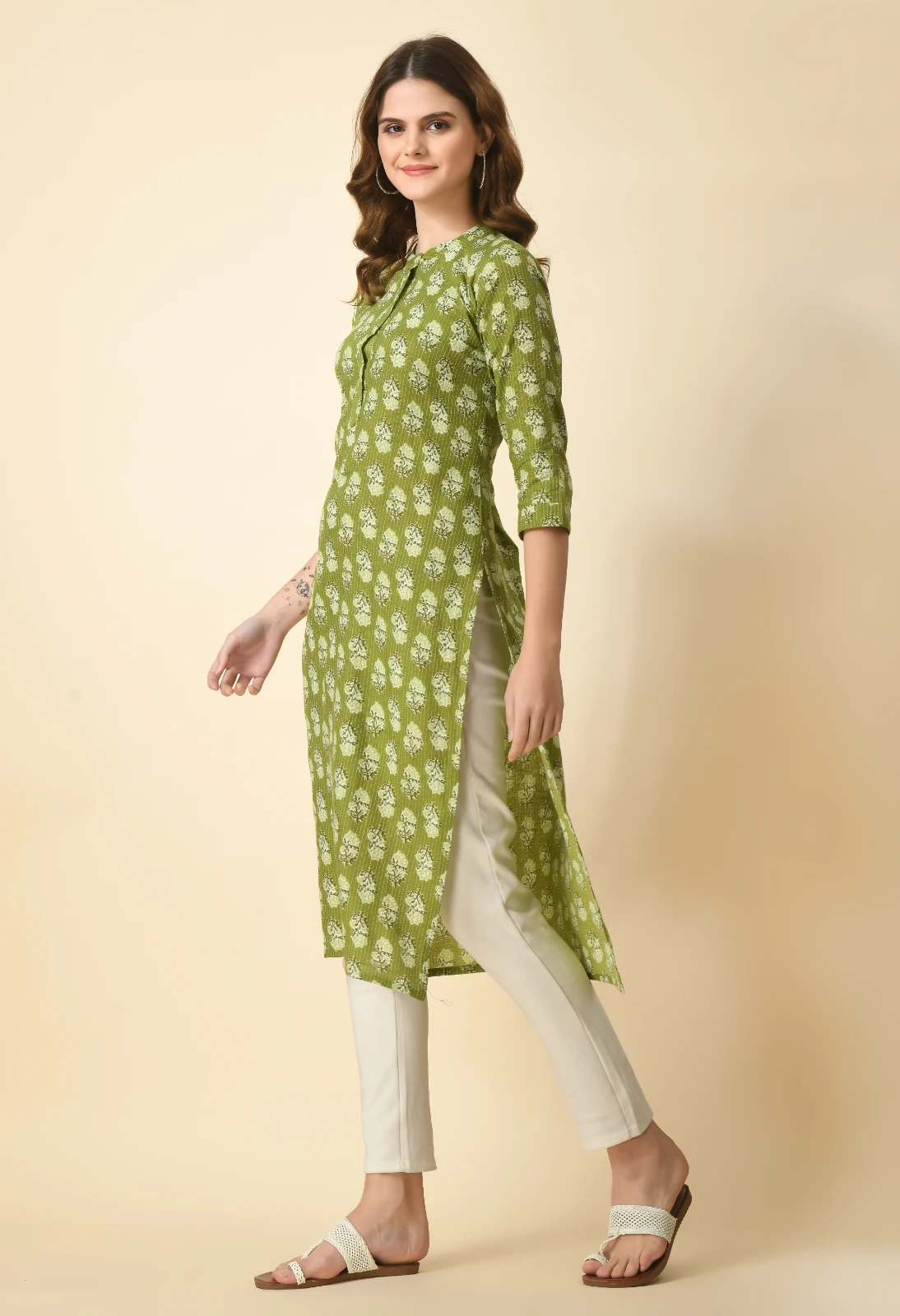 Left-side angled view of olive green printed kurta with side slit and off-white slim pants