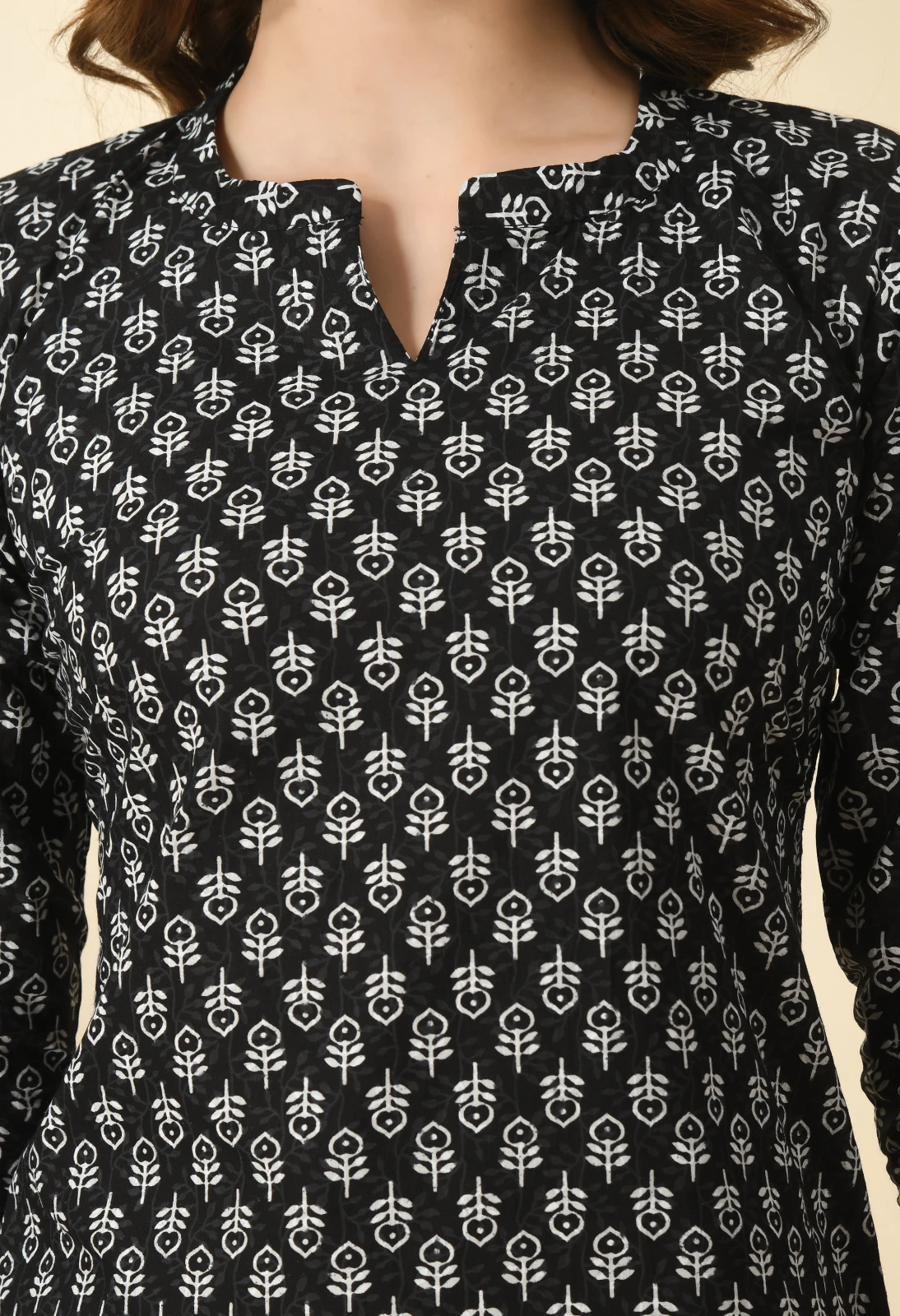 Close-up of the upper bodice showing the split notch neck and dense white motif pattern on black fabric