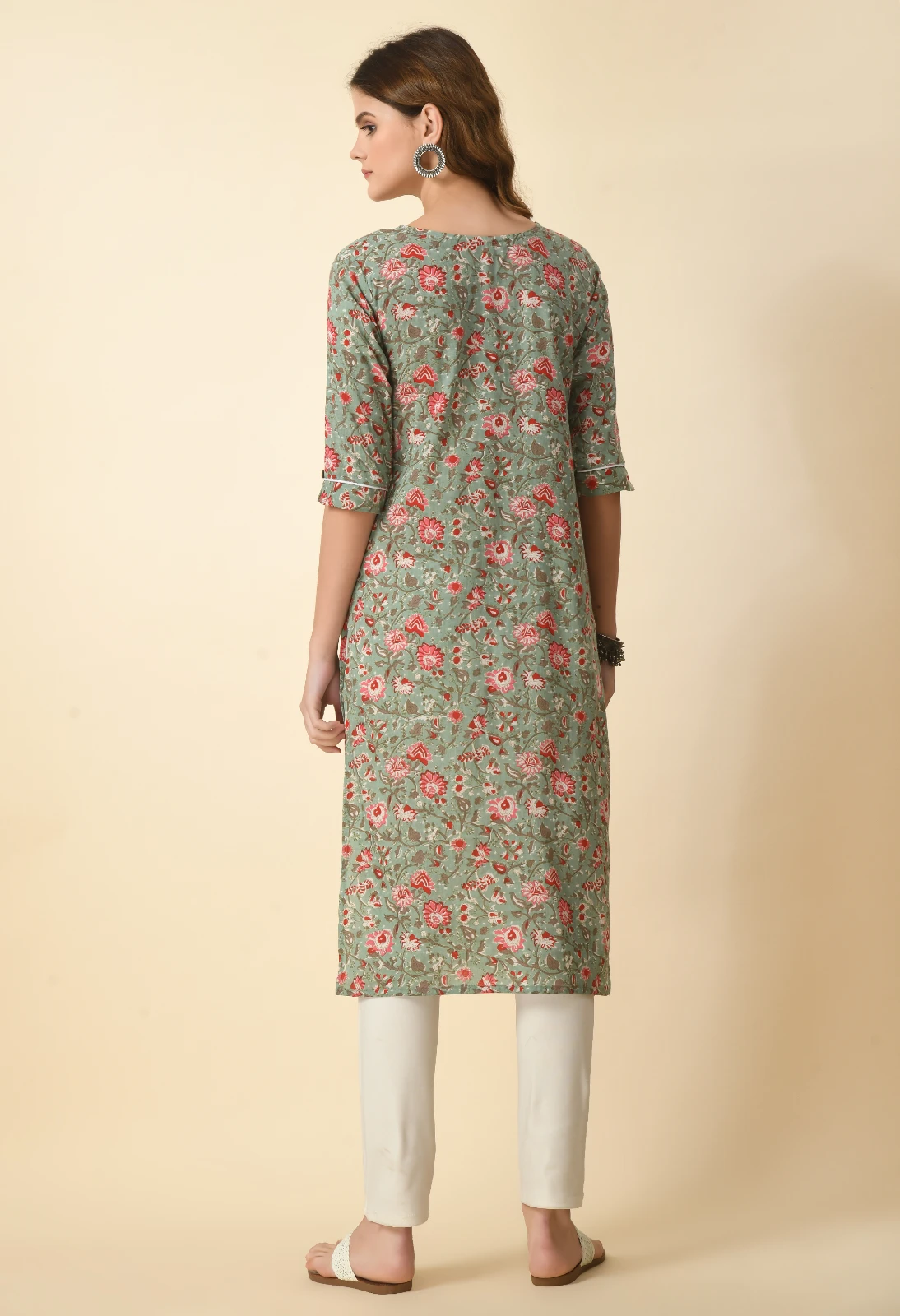 Back view of sage green floral kurta with three-quarter sleeves and straight hem over off-white pants