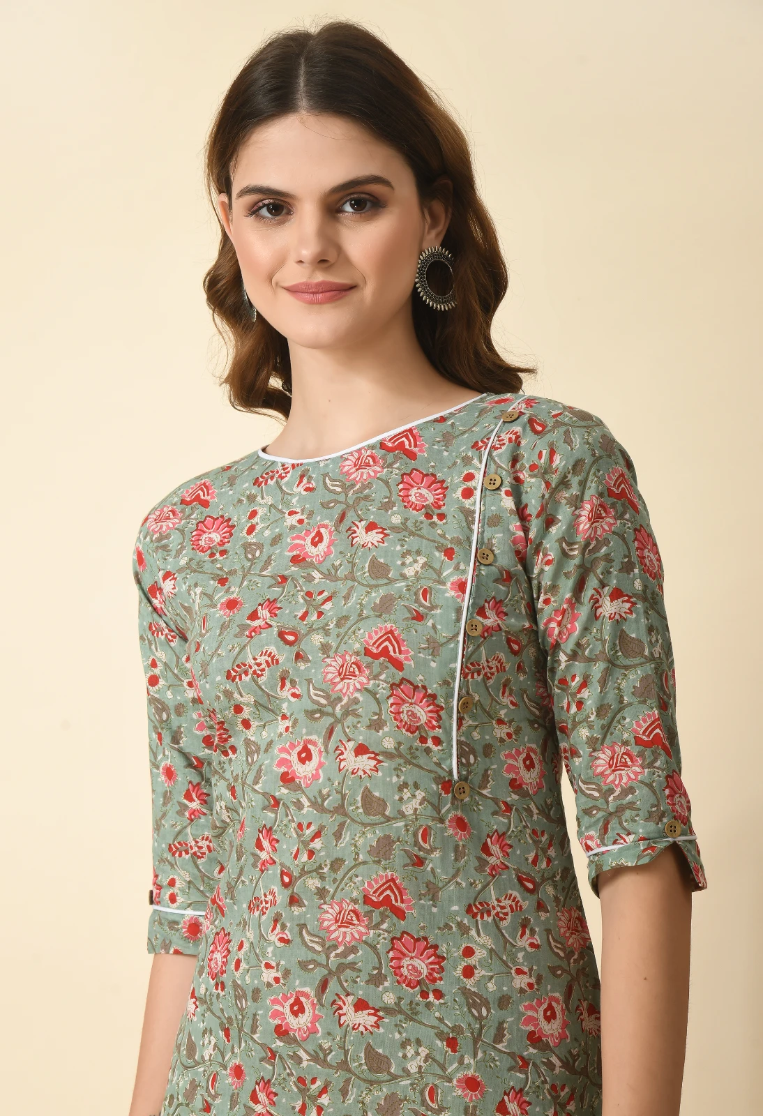 Close-up of round neckline with white piping and diagonal button detail on the printed bodice