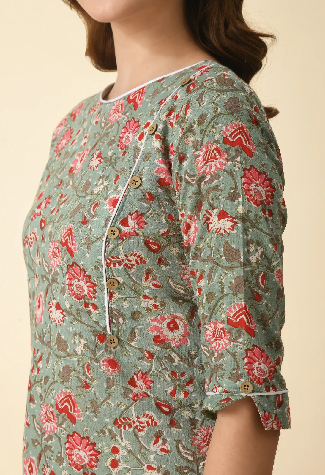 Detailed torso view of floral fabric, wooden-look buttons and sleeve cuff with piping and tab accent