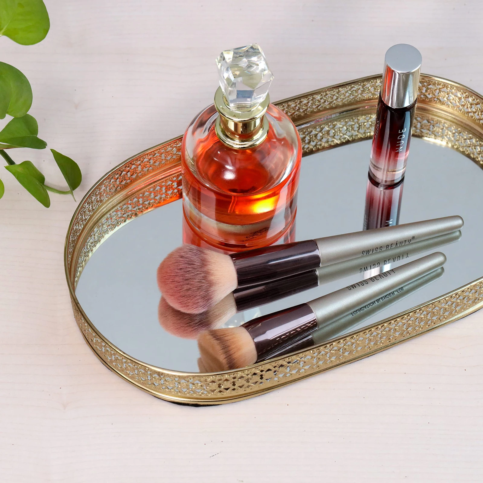 Gold mirrored vanity tray styled with perfume bottles and makeup brushes on a tabletop
