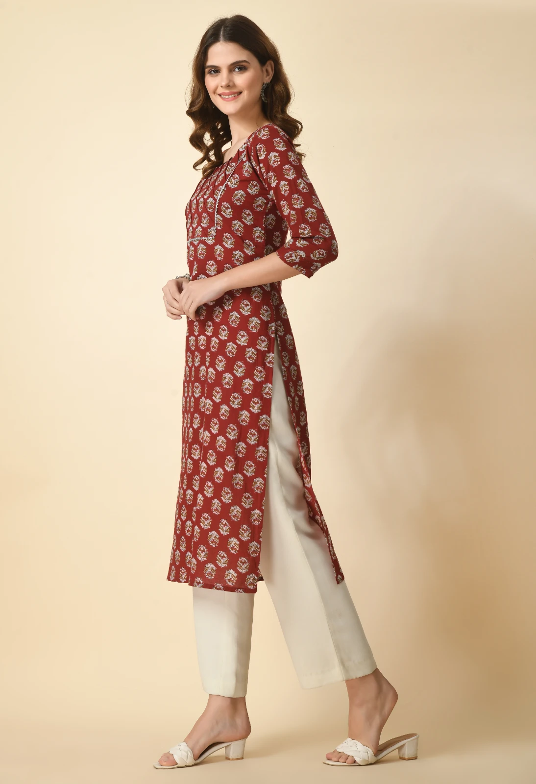 Side view of rust printed kurta showing high side slit, contrast piping and ivory wide-leg trousers