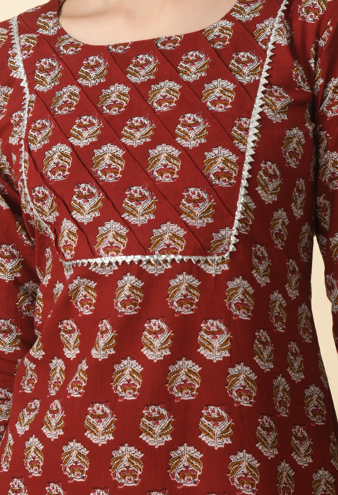 Close-up of diagonal pintuck bib with silver zigzag lace trim on rust printed kurta