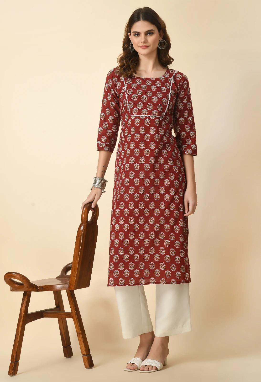 Full-length look of rust printed straight kurta styled with ivory wide-leg pants and white braided sandals