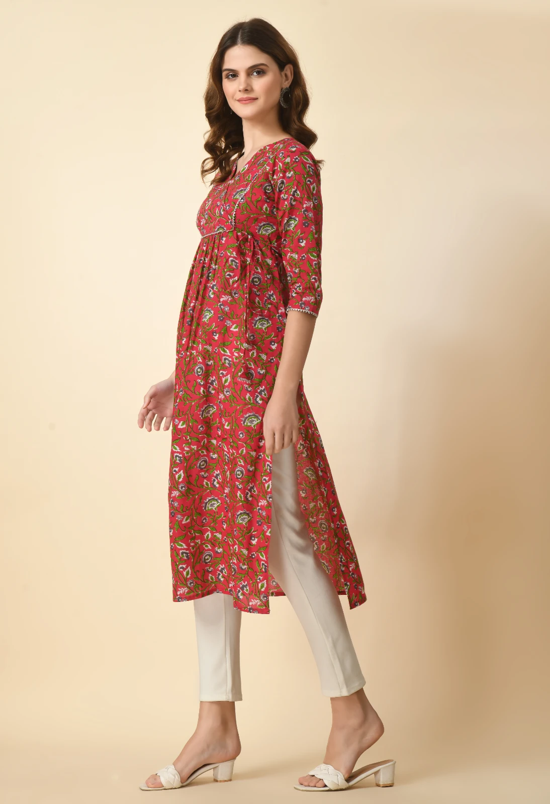Side view of the red floral kurta showing the long side slit and gathered waist over off-white pants