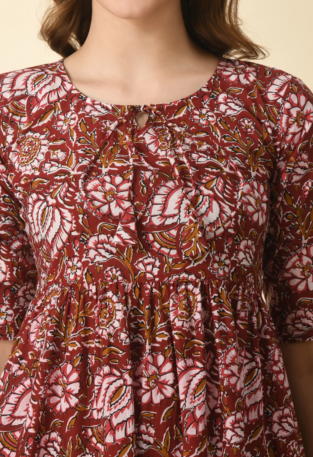 Close-up of the round keyhole neckline with tie detail and dense pink floral block print