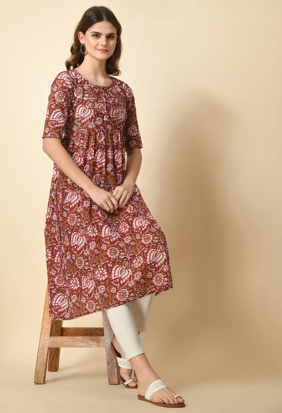 Seated styling view of the rust floral midi kurta paired with off-white leggings and flat sandals