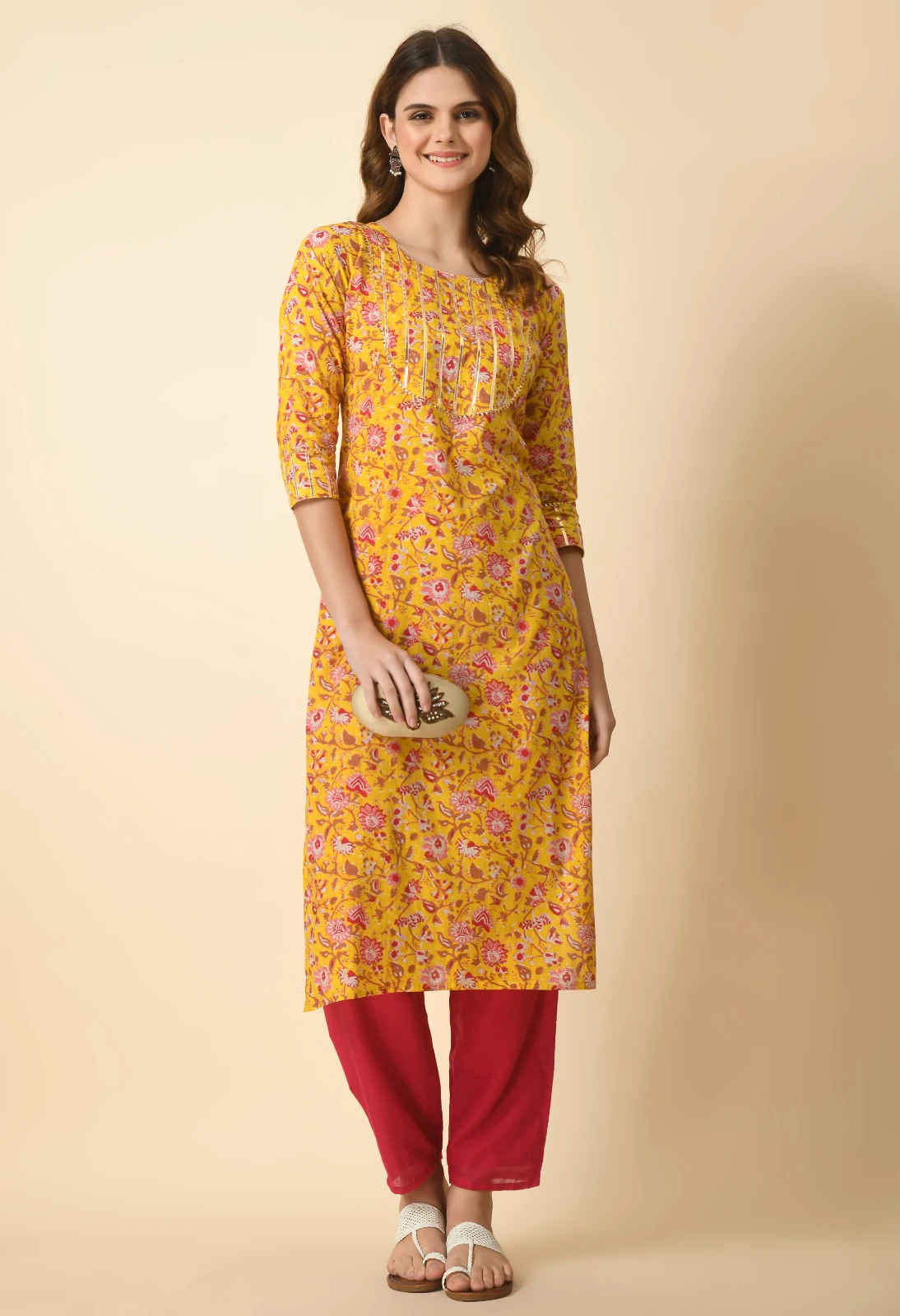 Mustard floral kurta styled with red straight pants, white sandals and a beige clutch