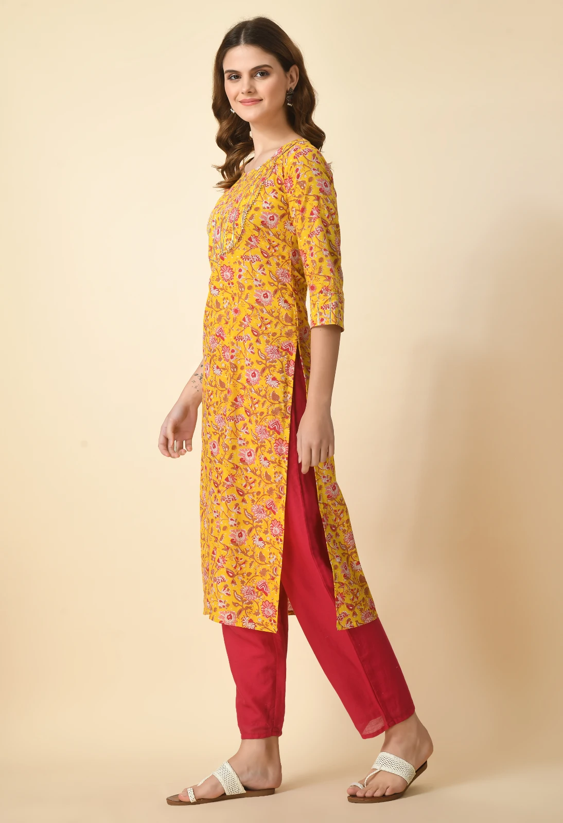 Left side view showing the long side slit of the mustard floral kurta over red pants