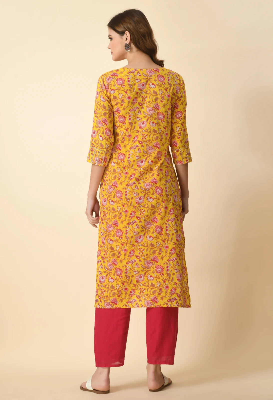 Back view of mustard floral kurta with three-quarter sleeves, shown with red pants and white slip-on sandals