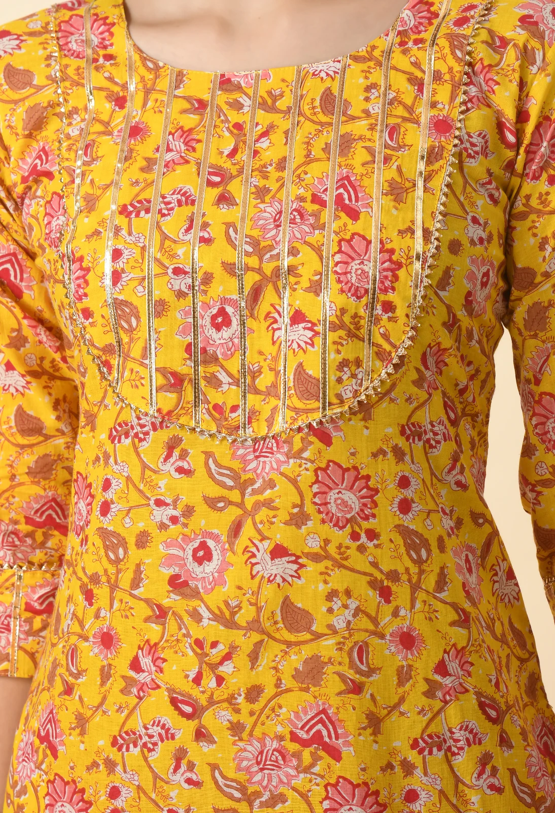 Detailed close-up of the mustard floral print with metallic pintuck panel and curved yoke trim