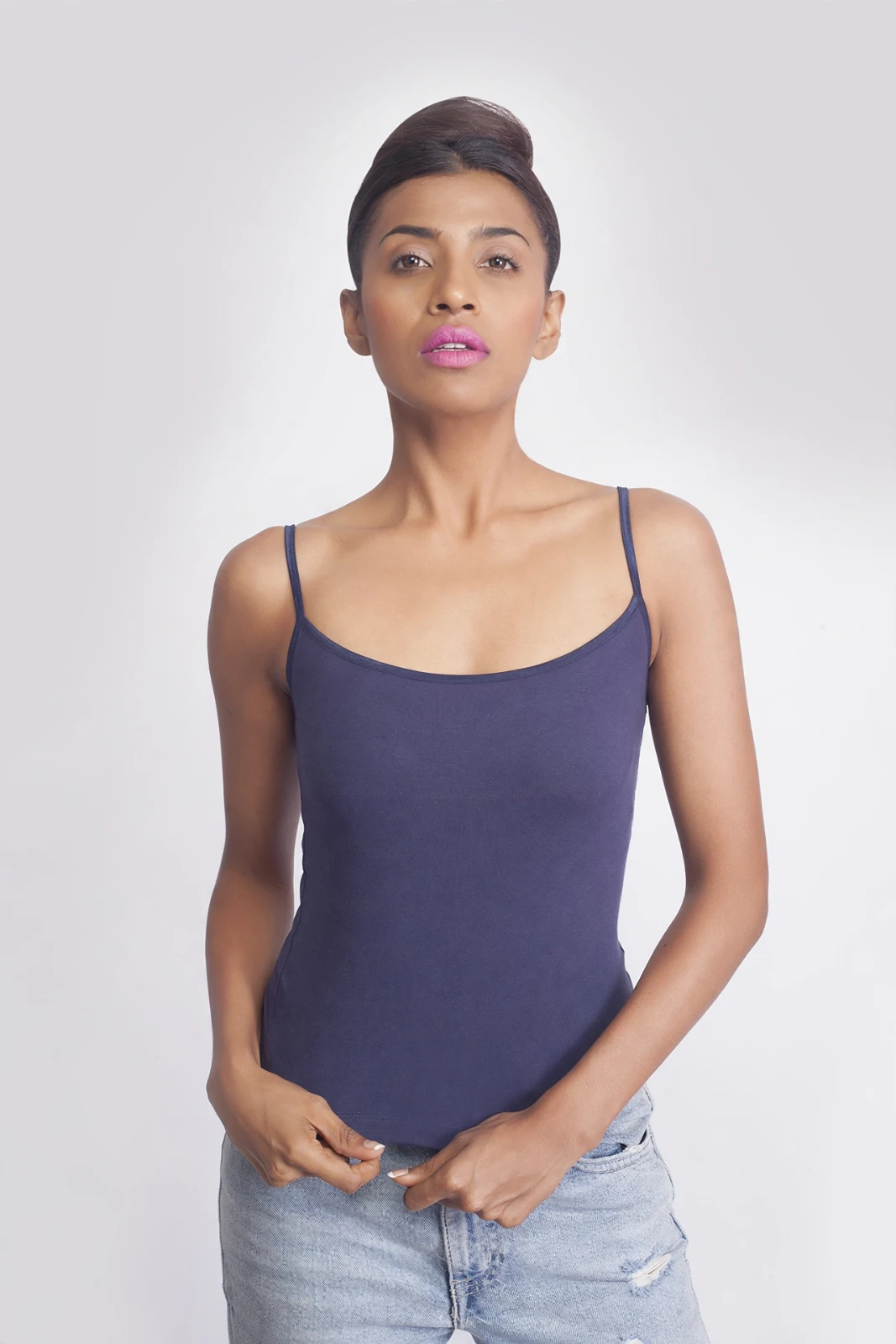 Women's navy fitted camisole front view on a model, styled with hands at the hem and light-wash jeans