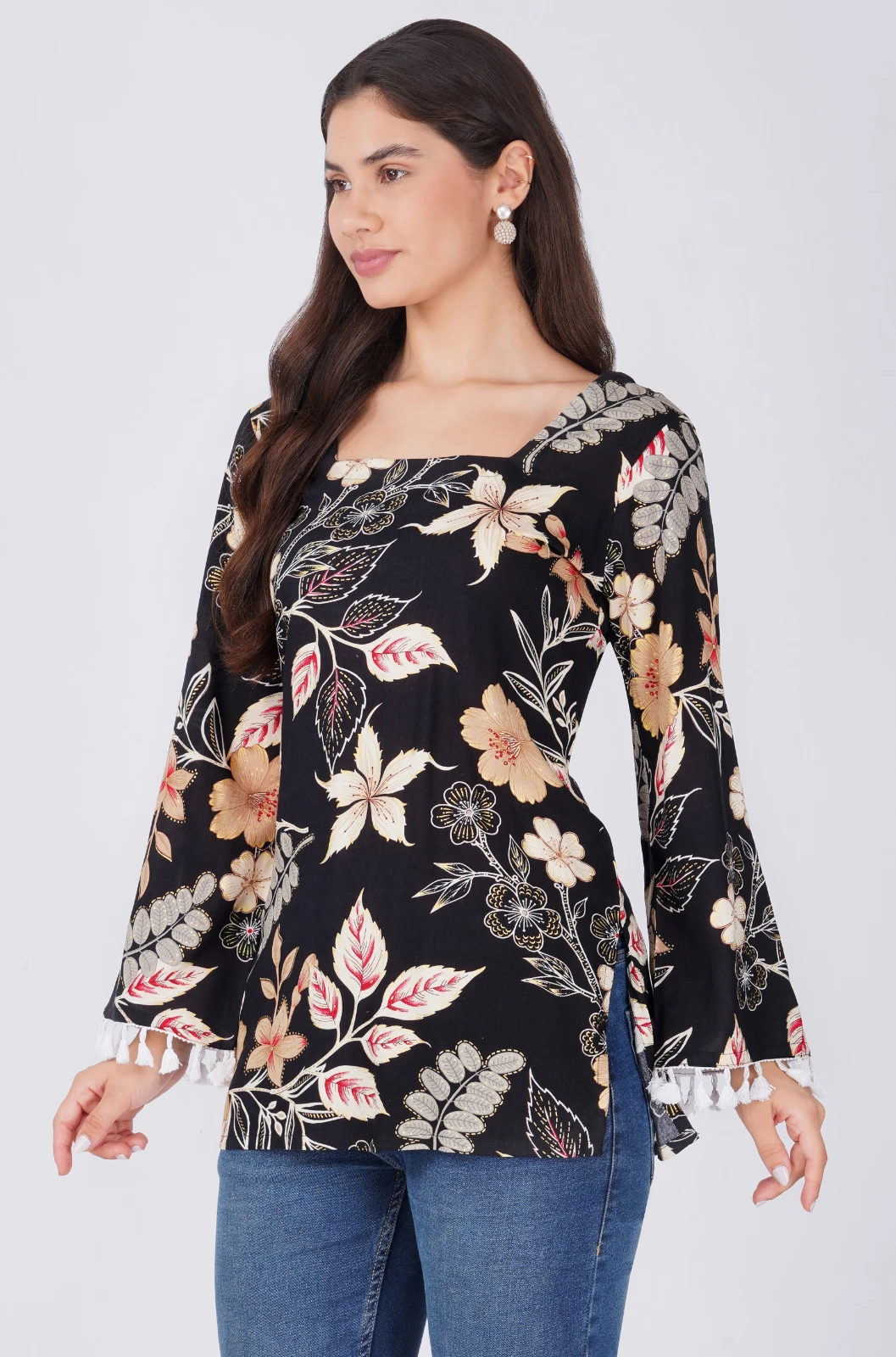 Full-length angled view showing black floral tunic top, flared tassel cuffs, and side slit hem