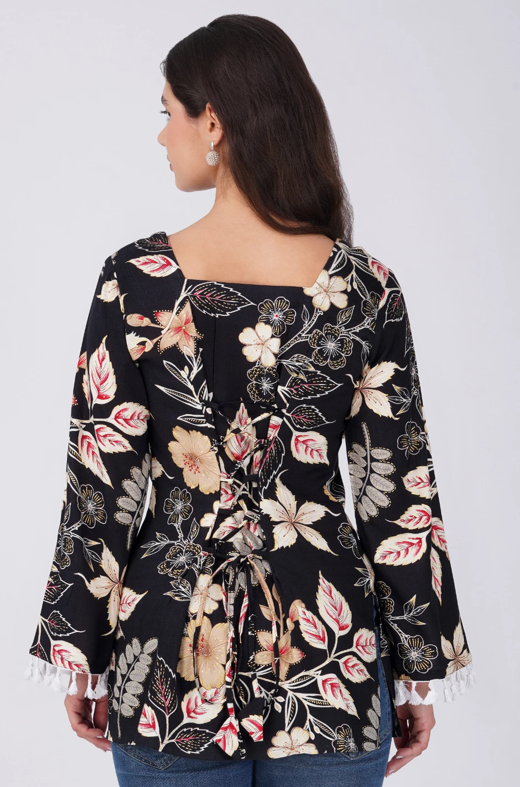 Front view of black floral top with square neckline and white tassel-trimmed bell sleeves