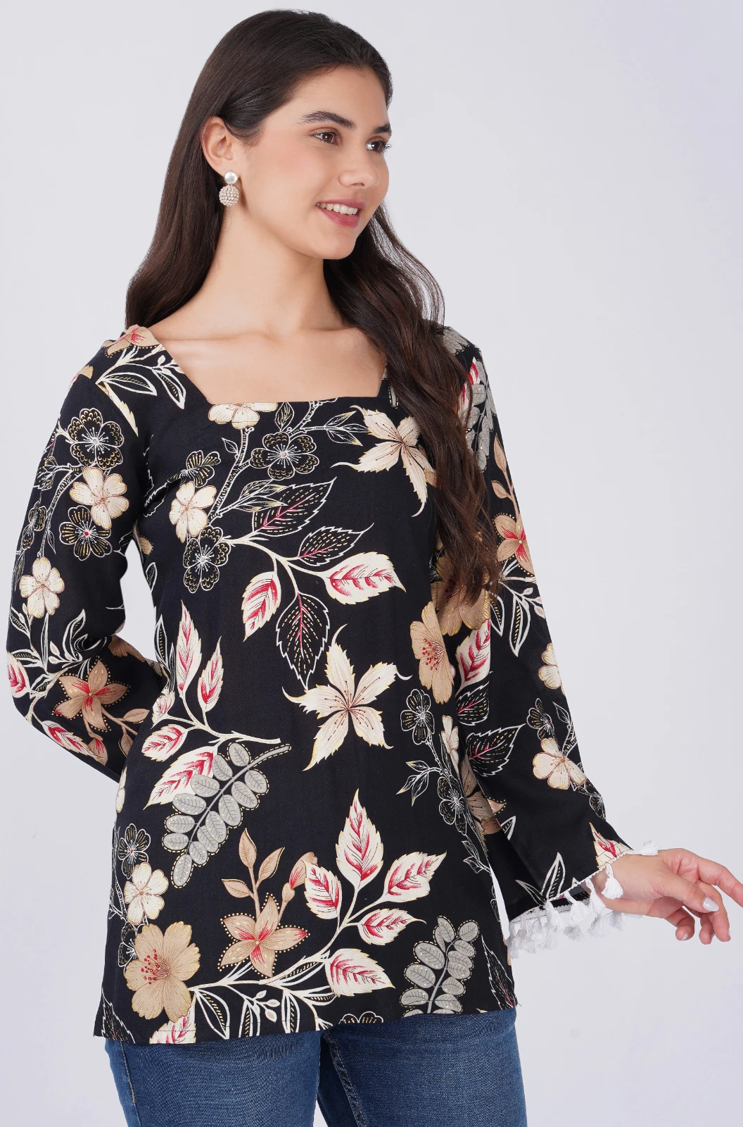 Front view of black floral top with square neckline and white tassel-trimmed bell sleeves