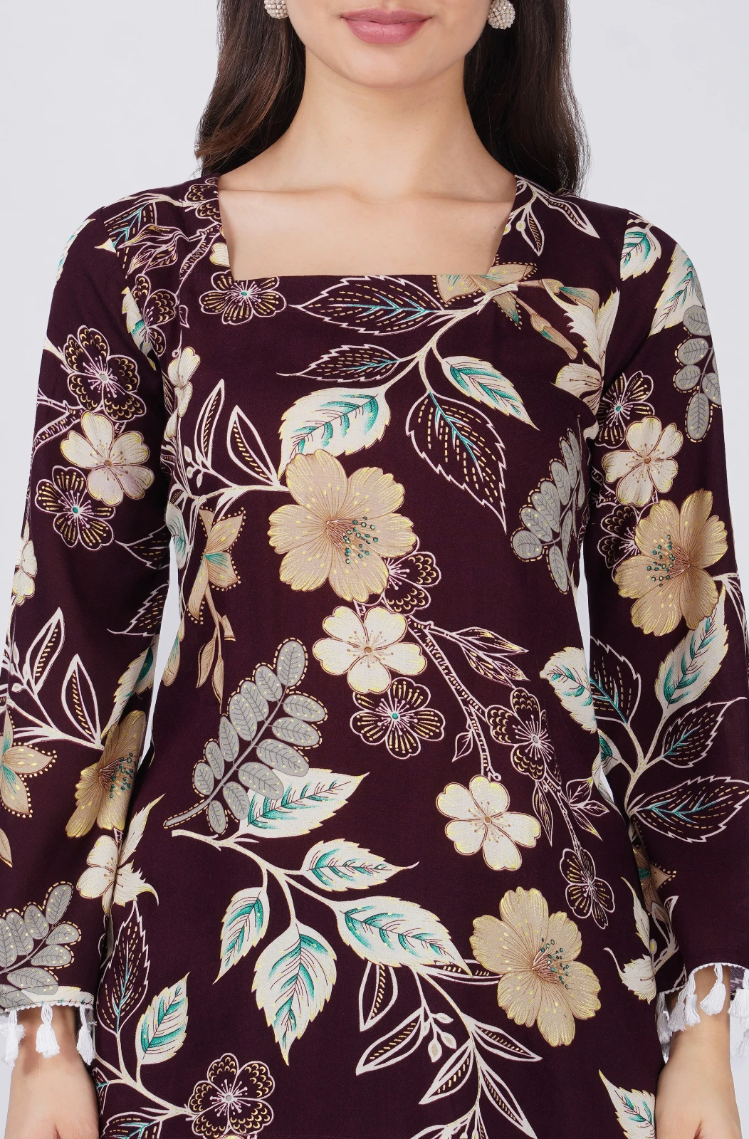 Close-up of square neckline and floral pattern in beige, cream and teal with tassel cuff edges