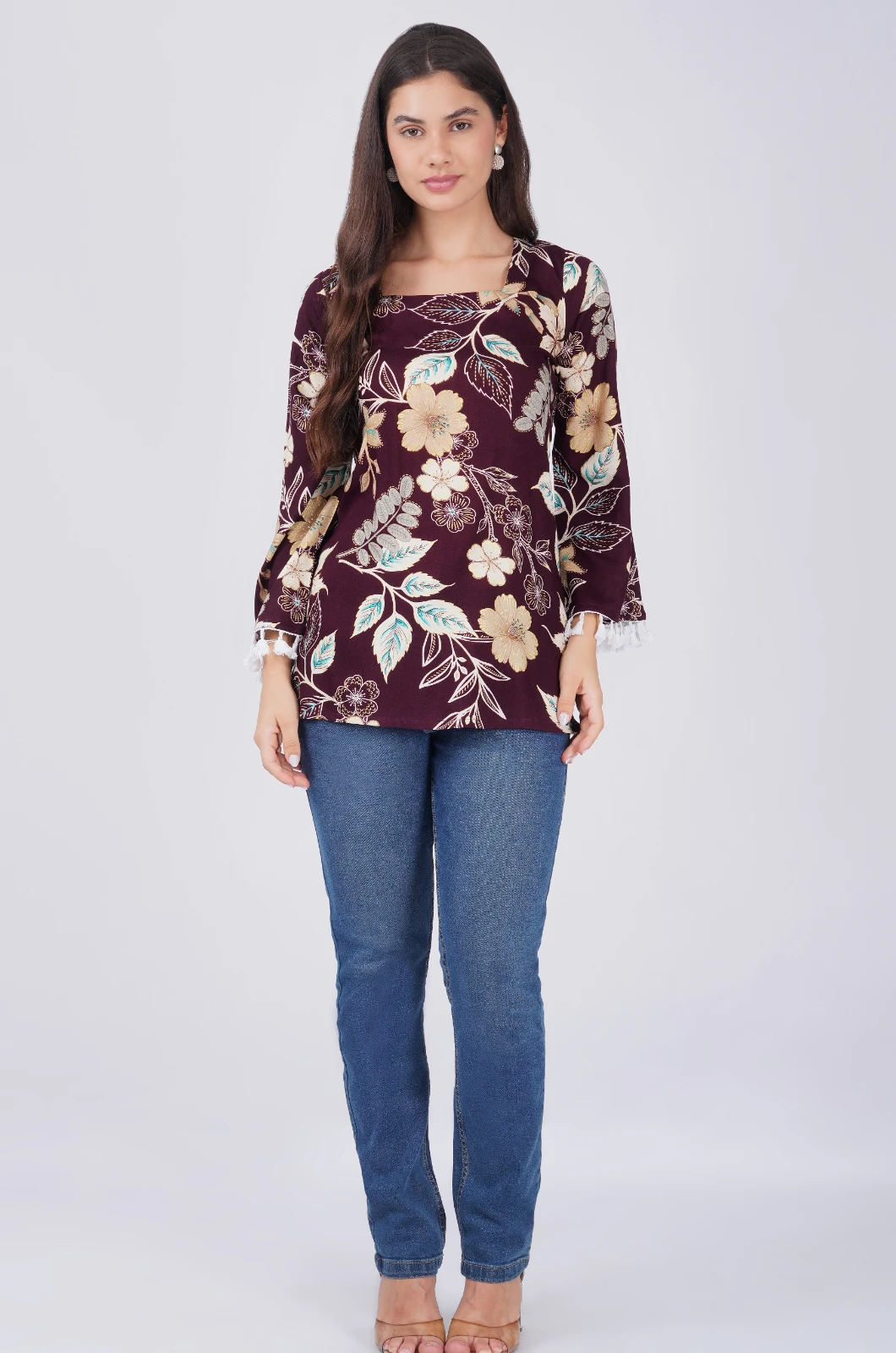 Full-length front view of the floral top paired with blue jeans and nude heels