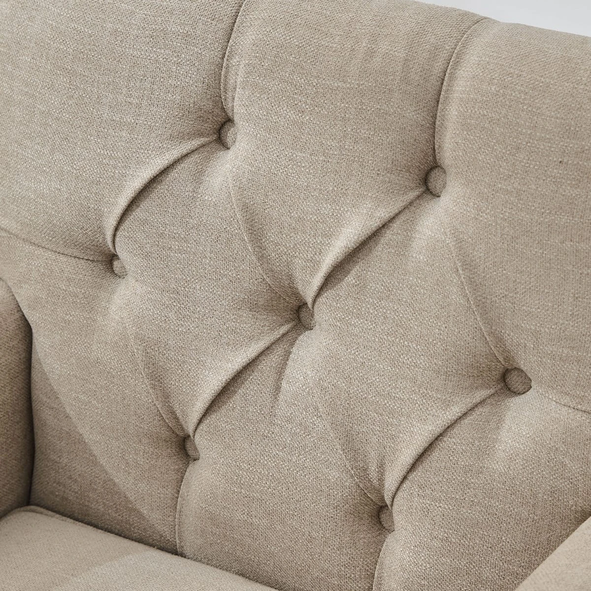 Close-up of the chair's brown fabric backrest showing button tufting and textured upholstery