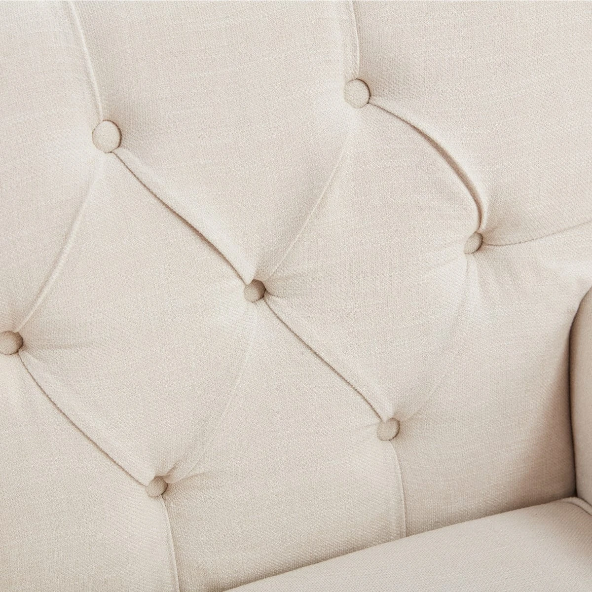 Close-up of the cream fabric backrest highlighting button tufting and textured upholstery
