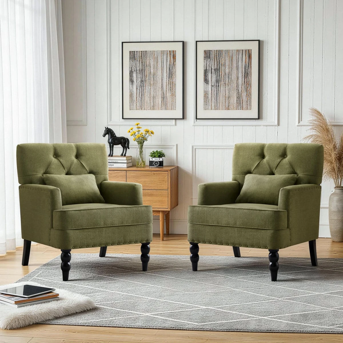 Two matching olive green accent chairs styled in a living room with a wood sideboard and wall art