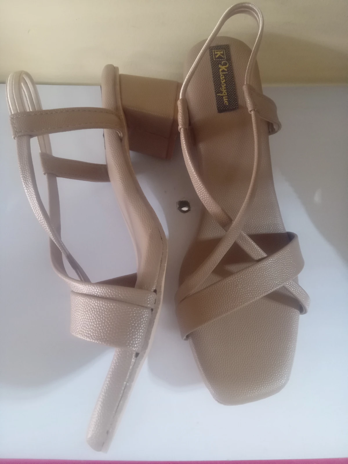 Top and side angle showing textured beige footbed, crossed front straps, and slingback heel strap