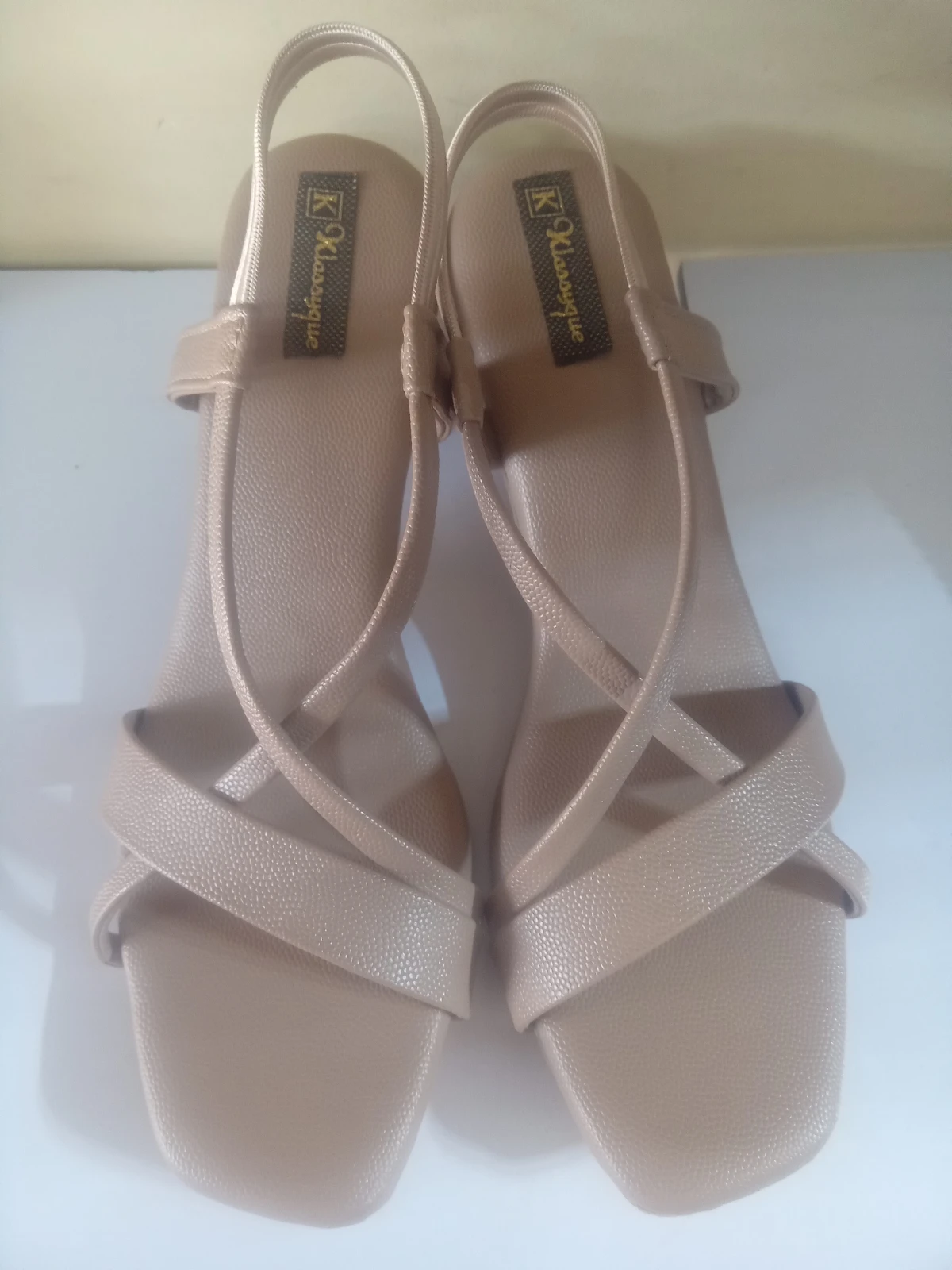 Top view of the pair highlighting square open toes, crisscross straps, and matching beige finish