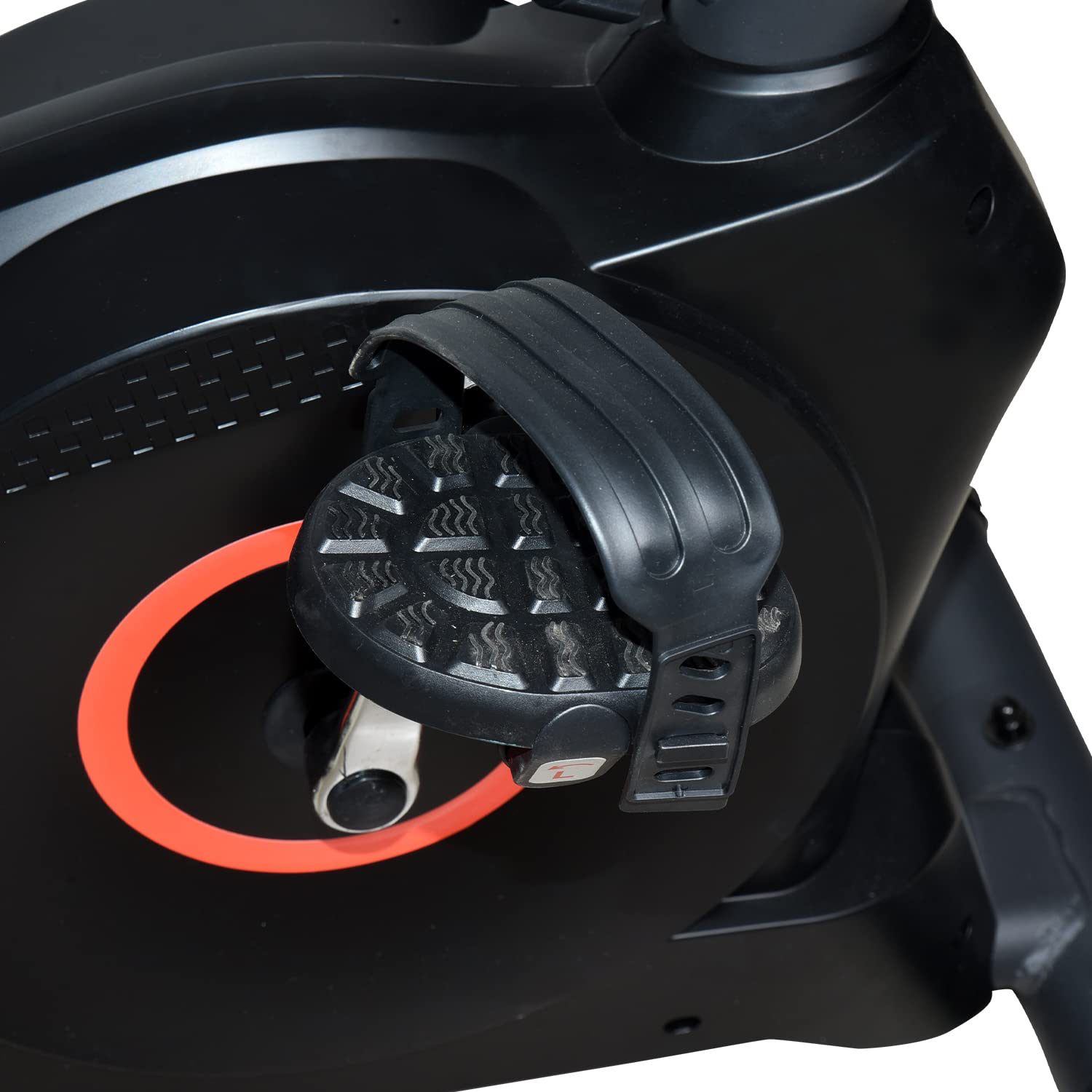 Close-up of exercise bike pedal with textured footplate and adjustable black strap beside red flywheel ring