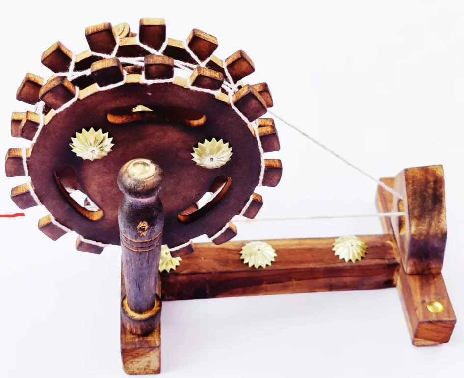 Front view of a handcrafted wooden spinning wheel showpiece with string detailing and carved floral accents