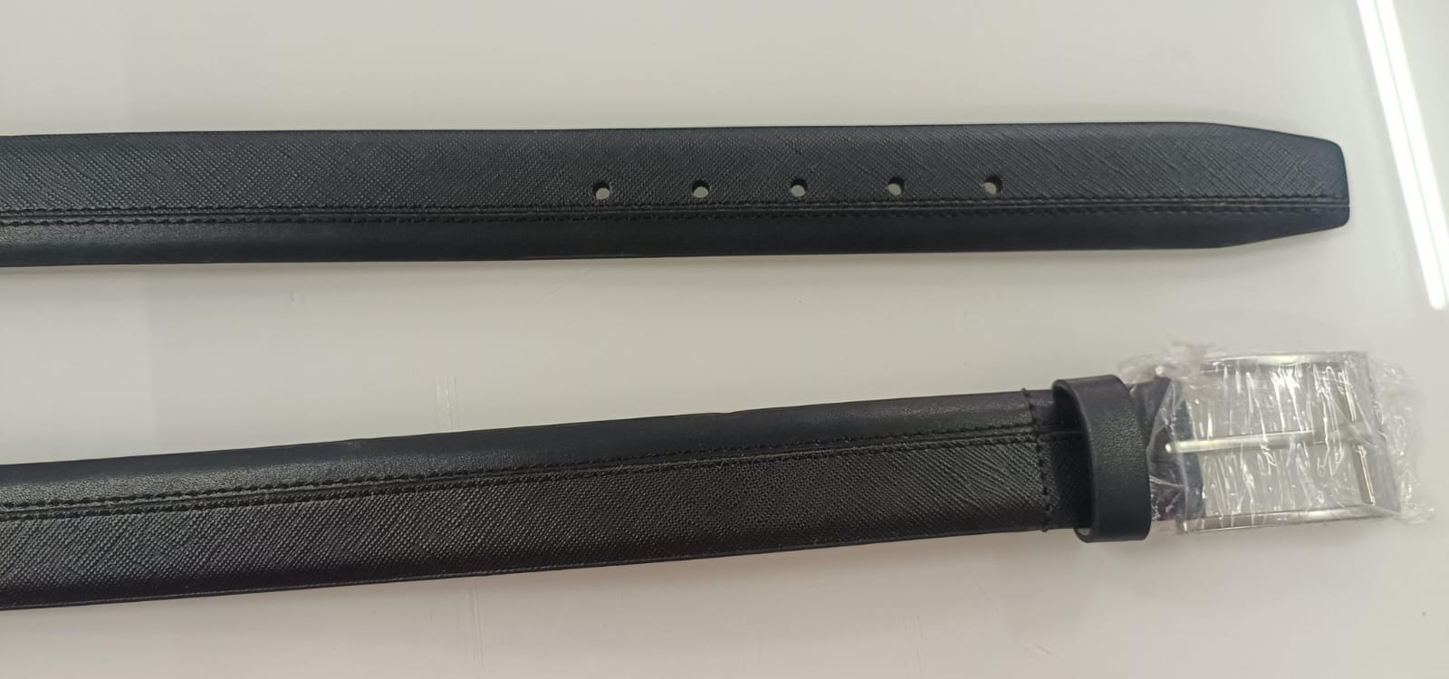 Brown belt coiled flat with smooth strap, keeper loop and shiny gold-tone pin buckle on white background