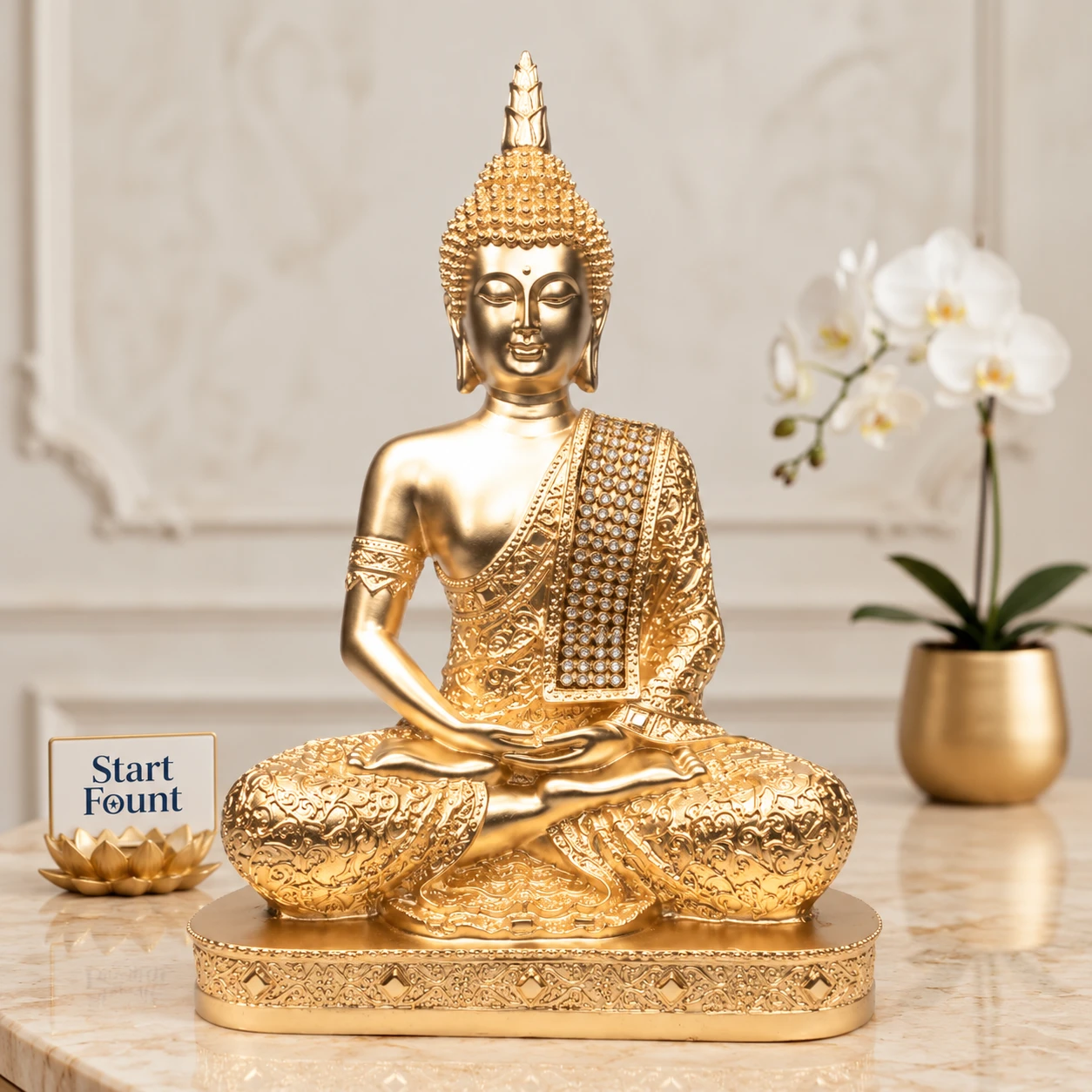 Front view of gold Buddha statue with ornate robe and jeweled drape on a decorative base