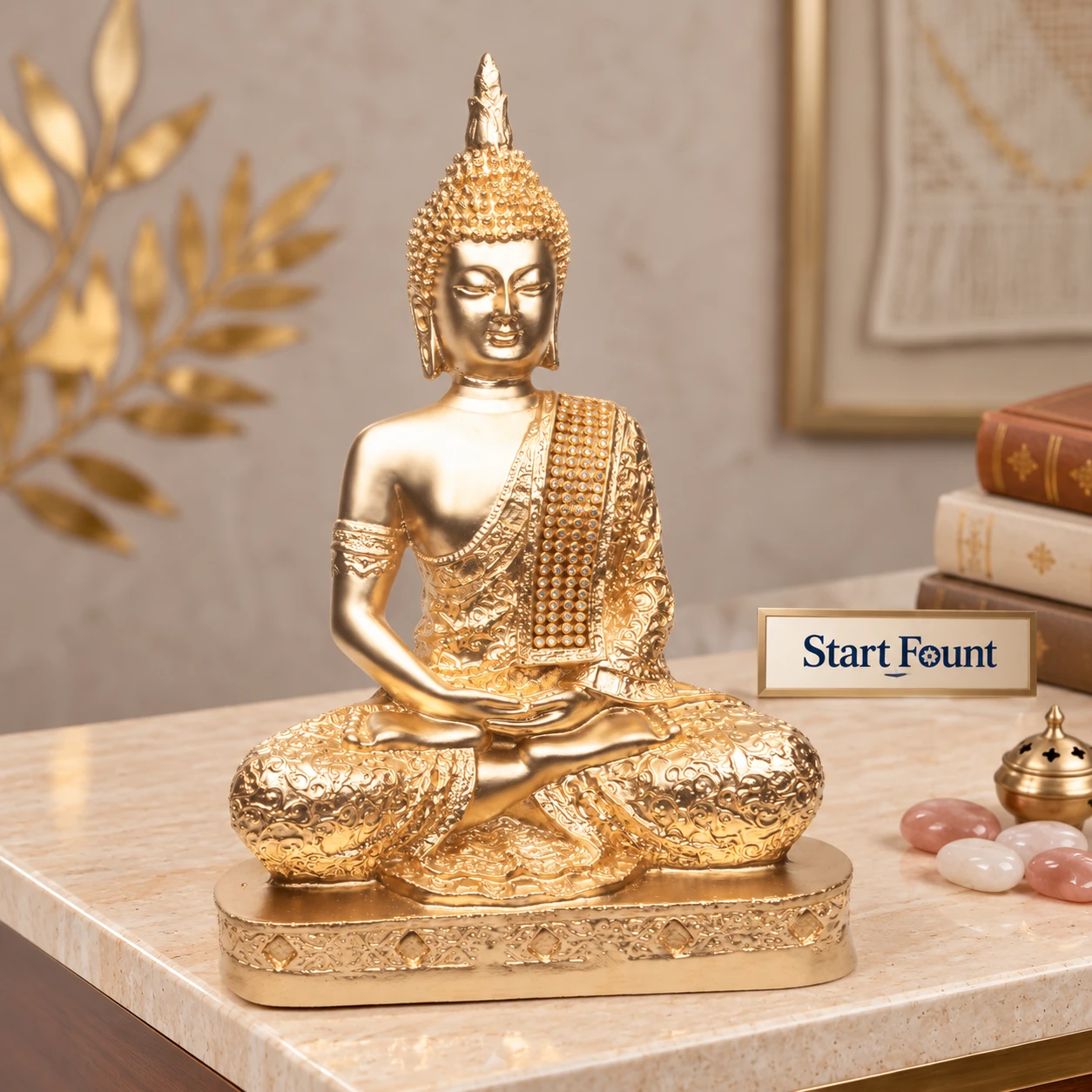 Front view of gold Buddha statue with ornate robe and jeweled drape on a decorative base