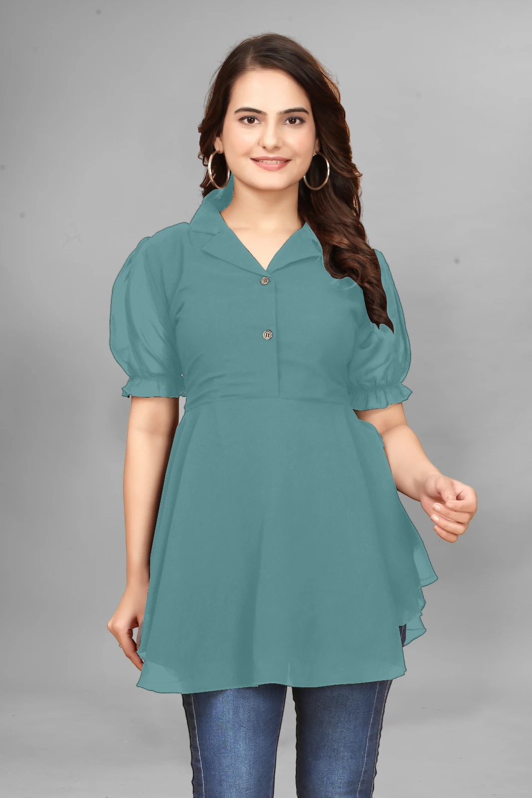 Woman wearing a teal peplum top with puff sleeves, dark jeans, hoop earrings and black sunglasses