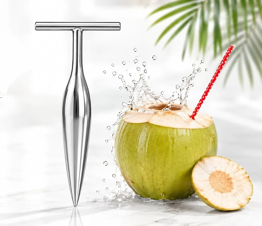 Stainless steel T-handle coconut opener beside a green tender coconut with straw and splash