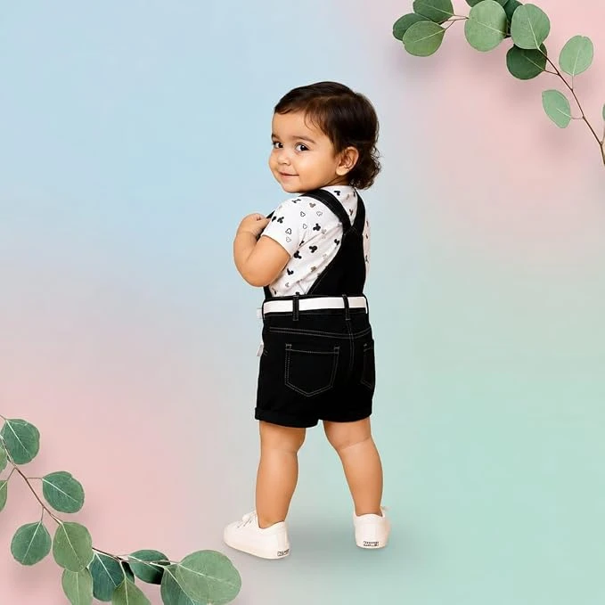Toddler wearing black dungaree romper with cartoon print over white printed T-shirt and white shoes