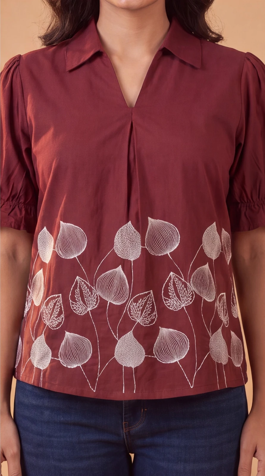 Women’s maroon puff sleeve top with collar and white leaf print, paired with blue jeans