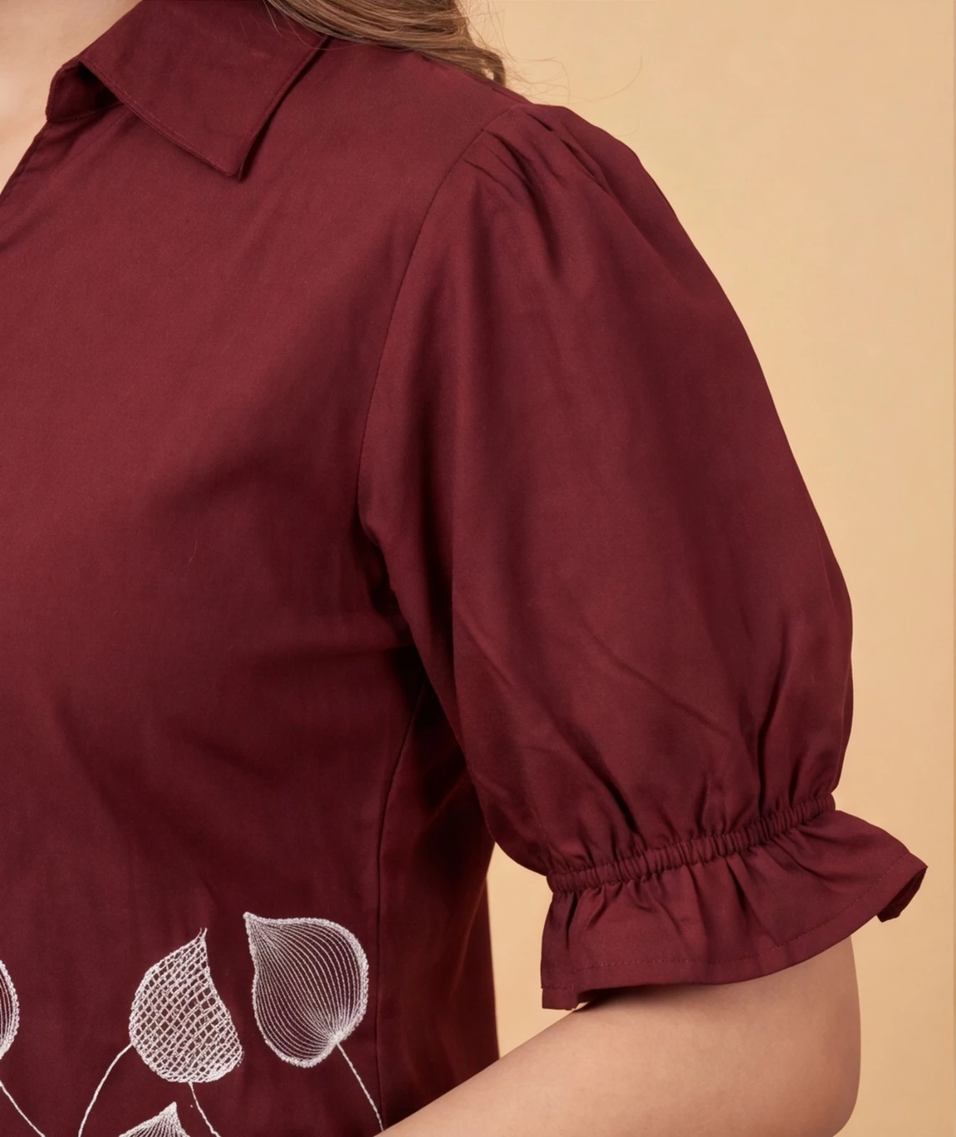Women’s maroon puff sleeve top with collar and white leaf print, paired with blue jeans
