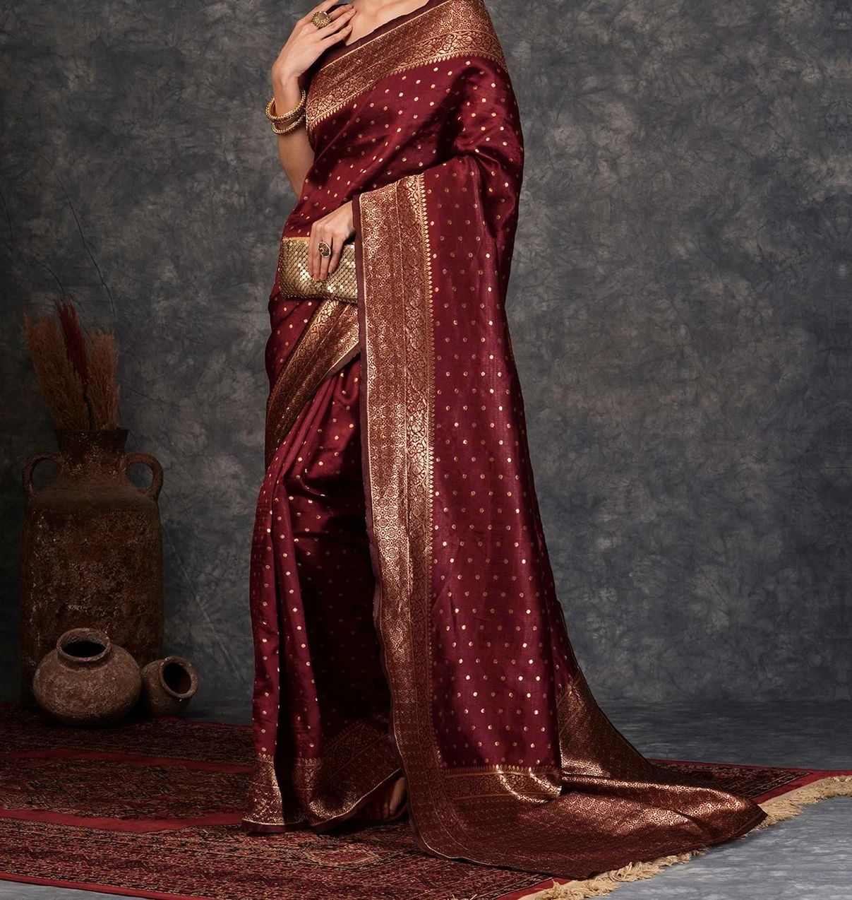 Woman wearing a maroon silk saree with gold zari border and dotted motifs at a festive event