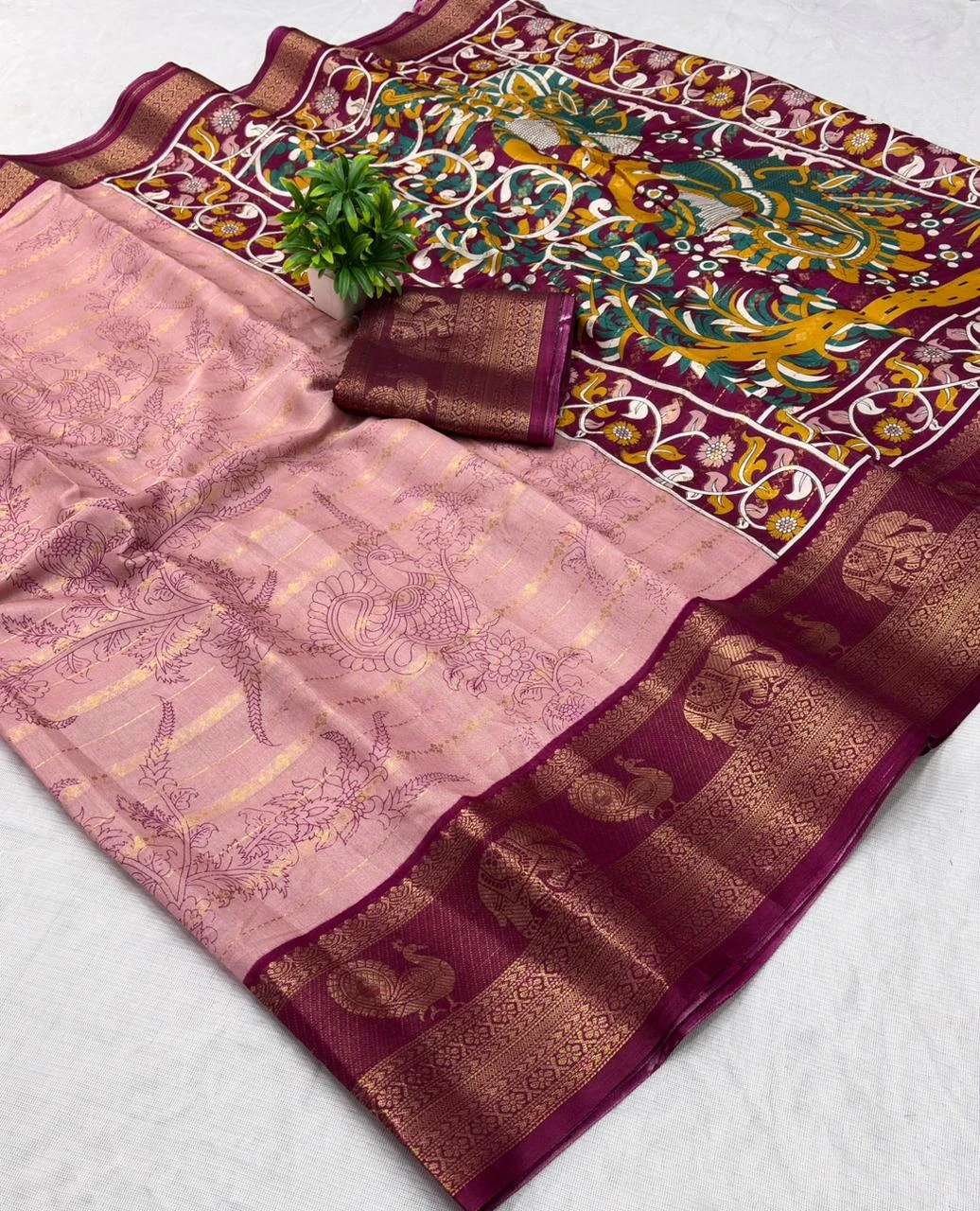 Pink silk saree with maroon gold zari border and elephant motifs, neatly draped and folded