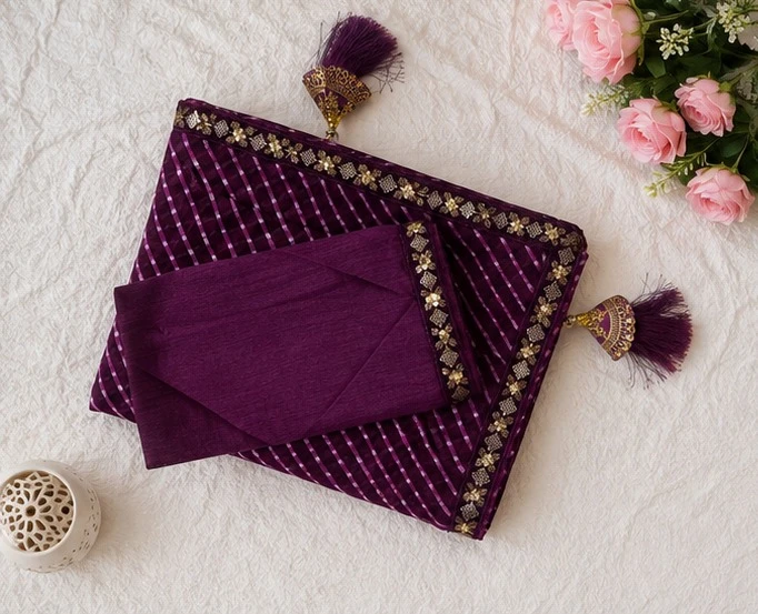 Woman wearing a purple striped saree with gold embroidered border and matching sleeveless blouse
