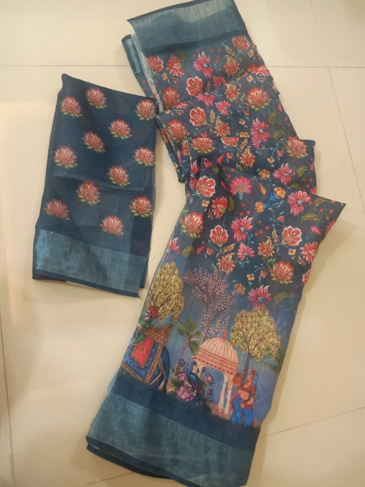 Woman wearing a blue floral printed saree with scenic border and matching blouse