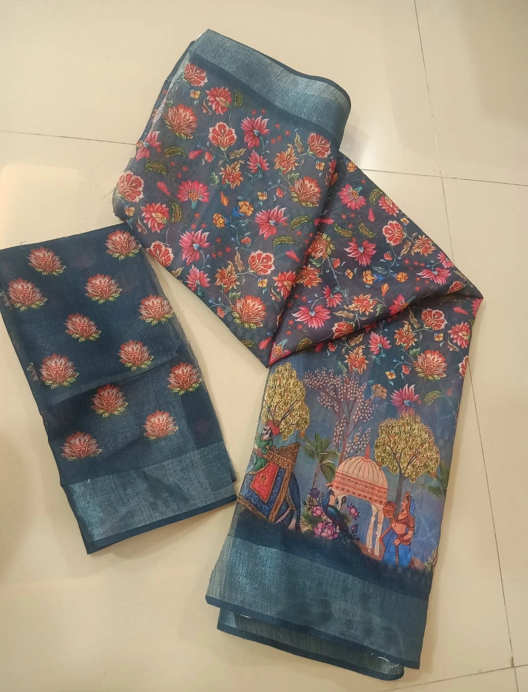 Woman wearing a blue floral printed saree with scenic border and matching blouse