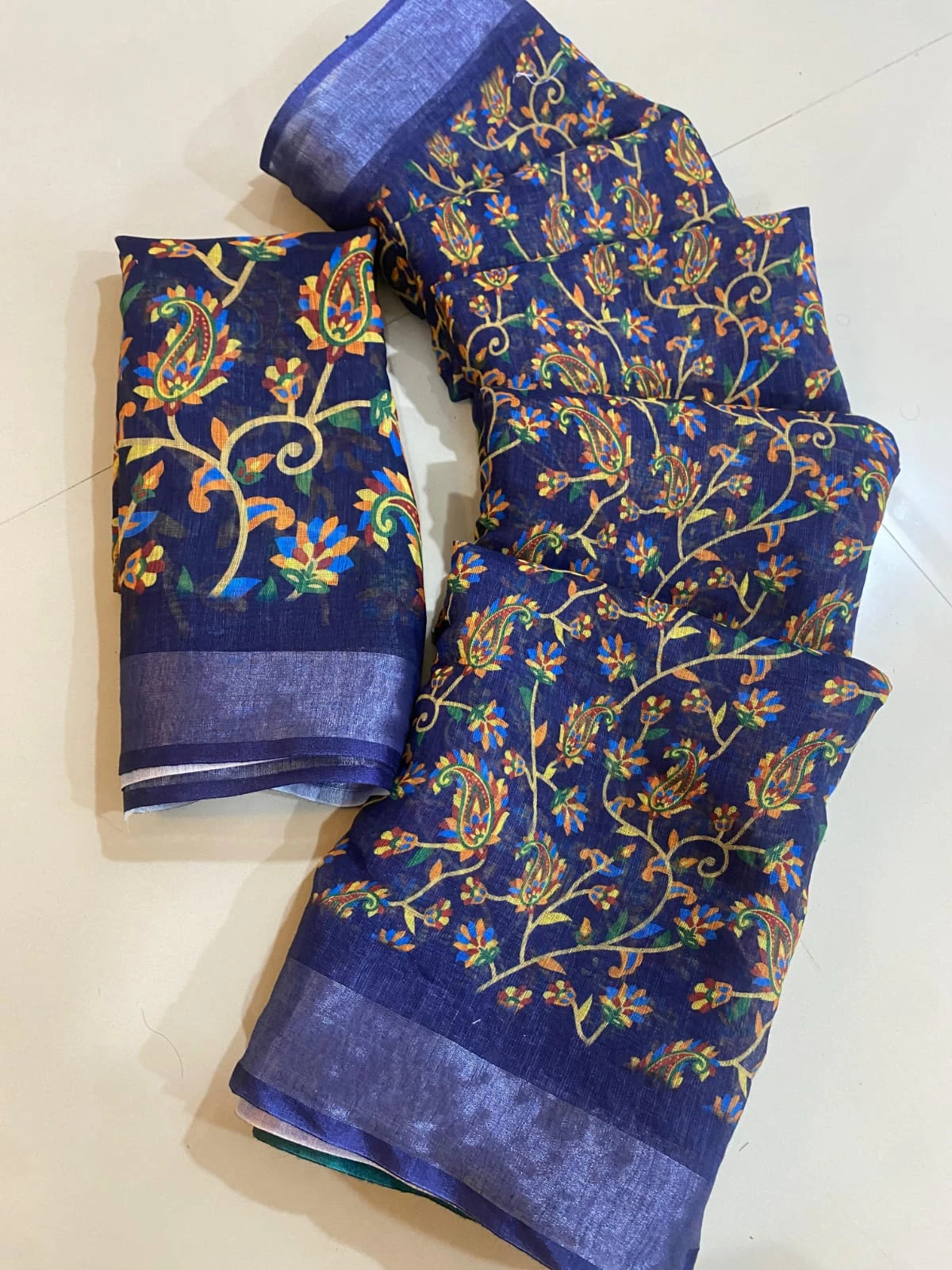Blue floral and paisley printed saree with matching blouse piece and solid border laid on floor