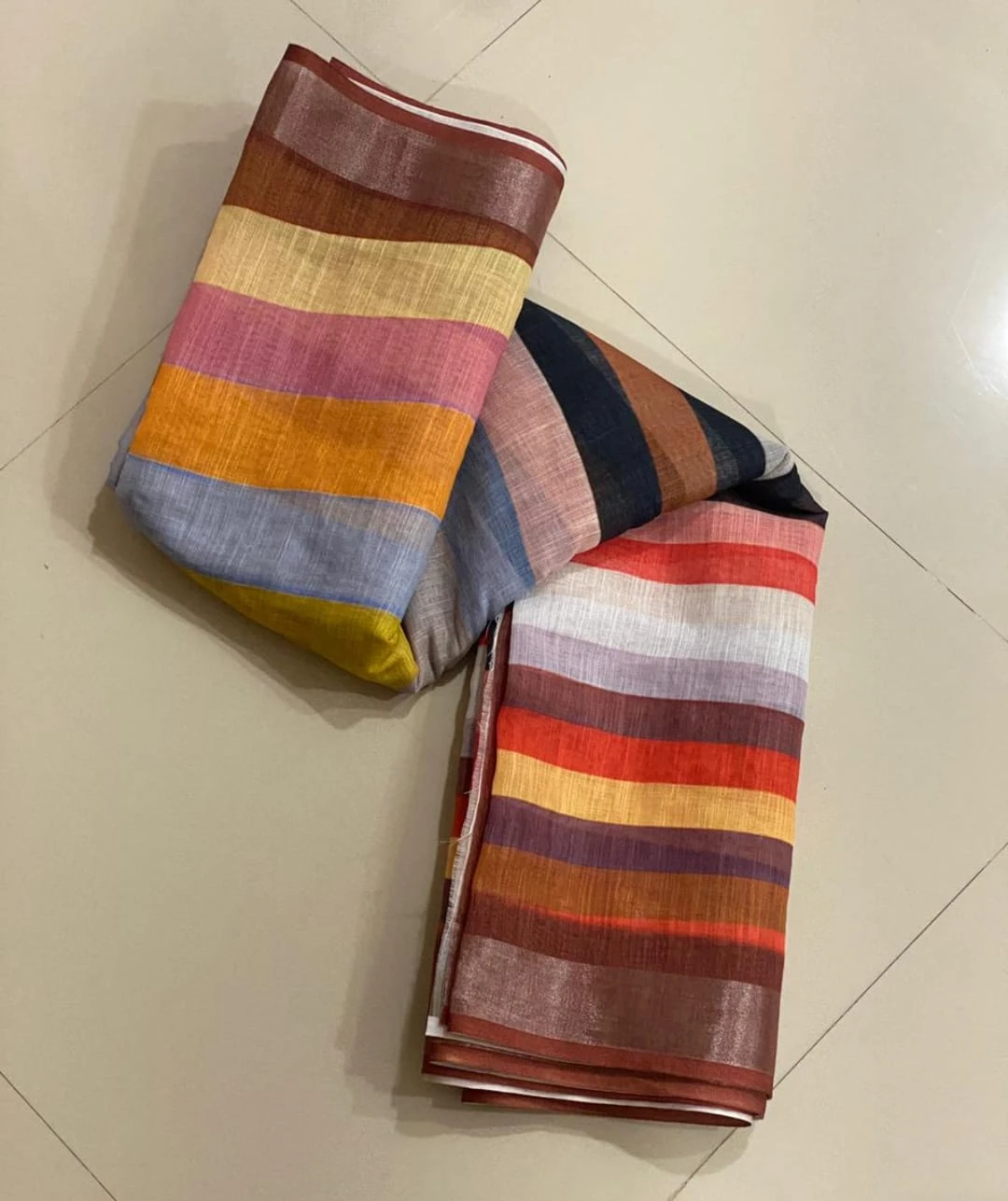 Woman wearing a multicolor striped saree with a brown blouse against a beige background