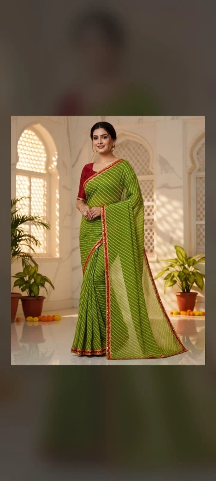 Woman wearing a green striped saree with red embellished border in an elegant indoor setting